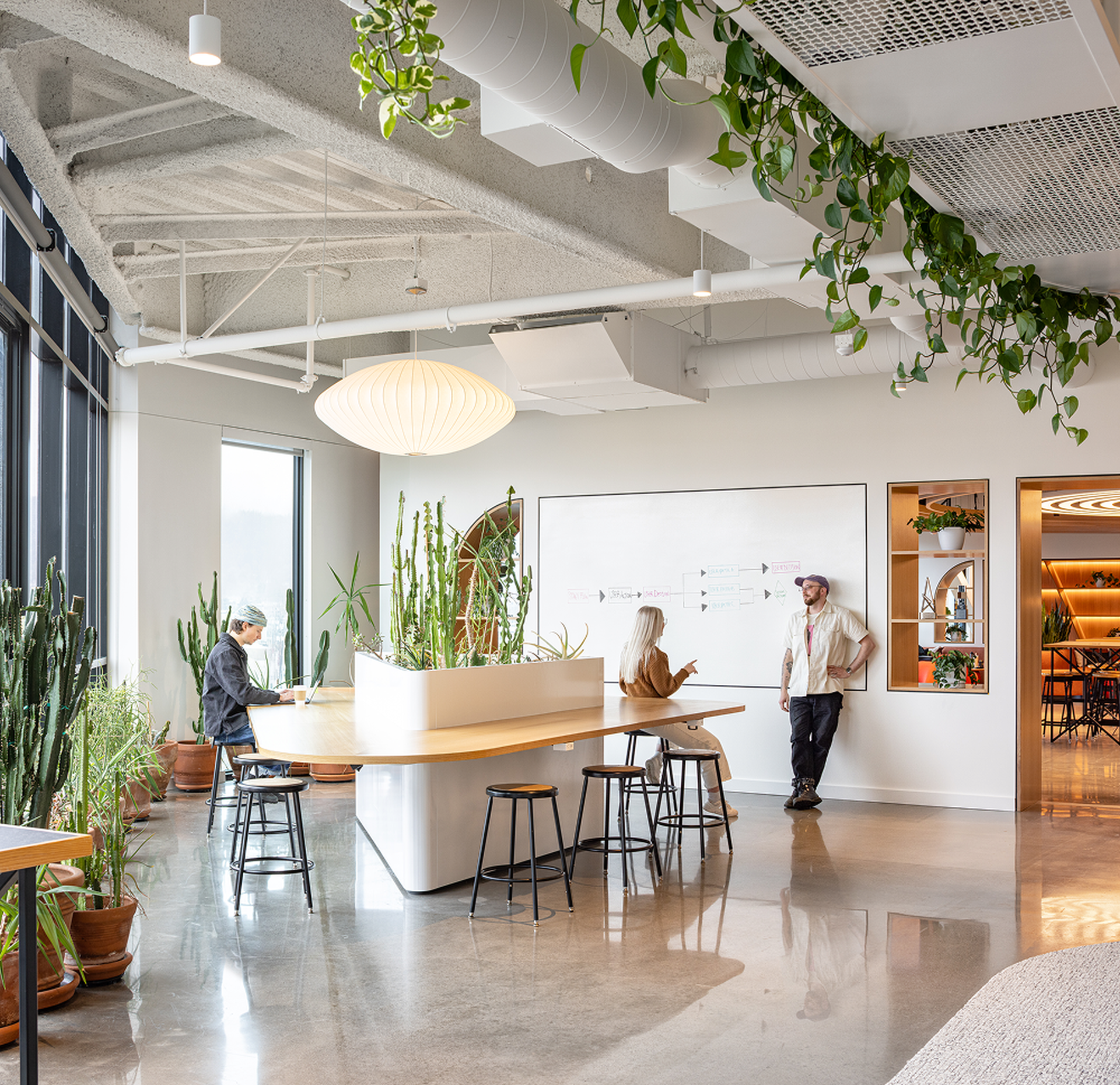 Bright office space with people discussing workflow at a whiteboard